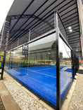 Cargar la imagen en la vista de la galería, Interior de cancha de padel profesional con vidrio templado y piso azul.
