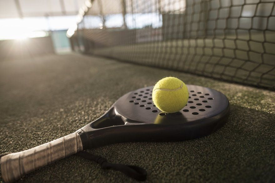 Pelota de pádel encima de Pala de pádel en campo de juego  