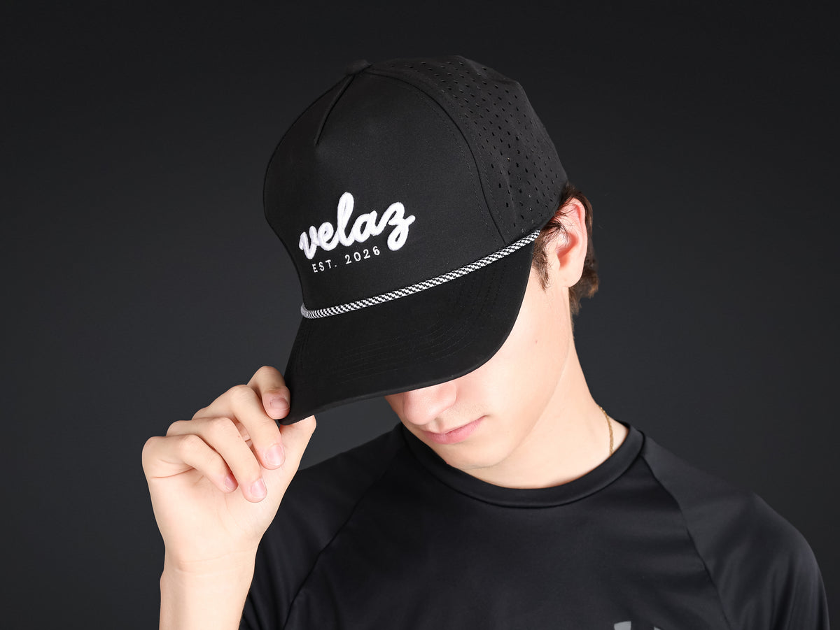 Jugador ajustándose la gorra deportiva negra Velaz con visera curvada.