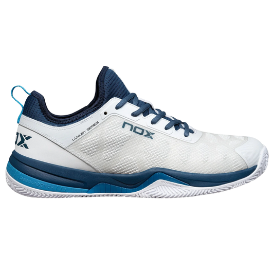 Tenis de pádel Nox Luxury Series en color blanco y azul. Diseño con suela de espiga de alto agarre, amortiguación Rebound Core y estabilizador lateral para evitar lesiones. 