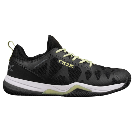 Tenis de pádel Nox Nerbo en color negro con detalles vibrantes en lima suave. Vista del diseño ergonómico con suela mixta de espiga y tacos, estabilizadores latearles y logotipo de Nox en el lateral.  