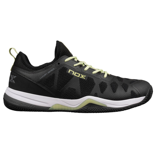 Tenis de pádel Nox Nerbo en color negro con detalles vibrantes en lima suave. Vista del diseño ergonómico con suela mixta de espiga y tacos, estabilizadores latearles y logotipo de Nox en el lateral.  